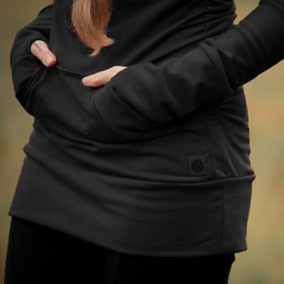 Person wearing a black sweater with pockets with a blurred background